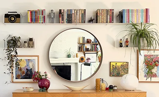 Stylish home decoration with mirror, plants, and colorful books.
